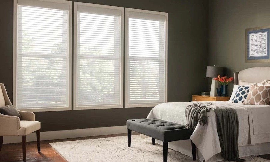 white automated horizontal blinds installed in three windows of a bedroom.