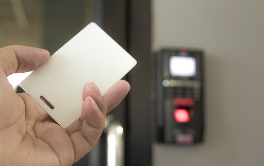 close-up shot of a hand holding a keycard with an entry console in the background